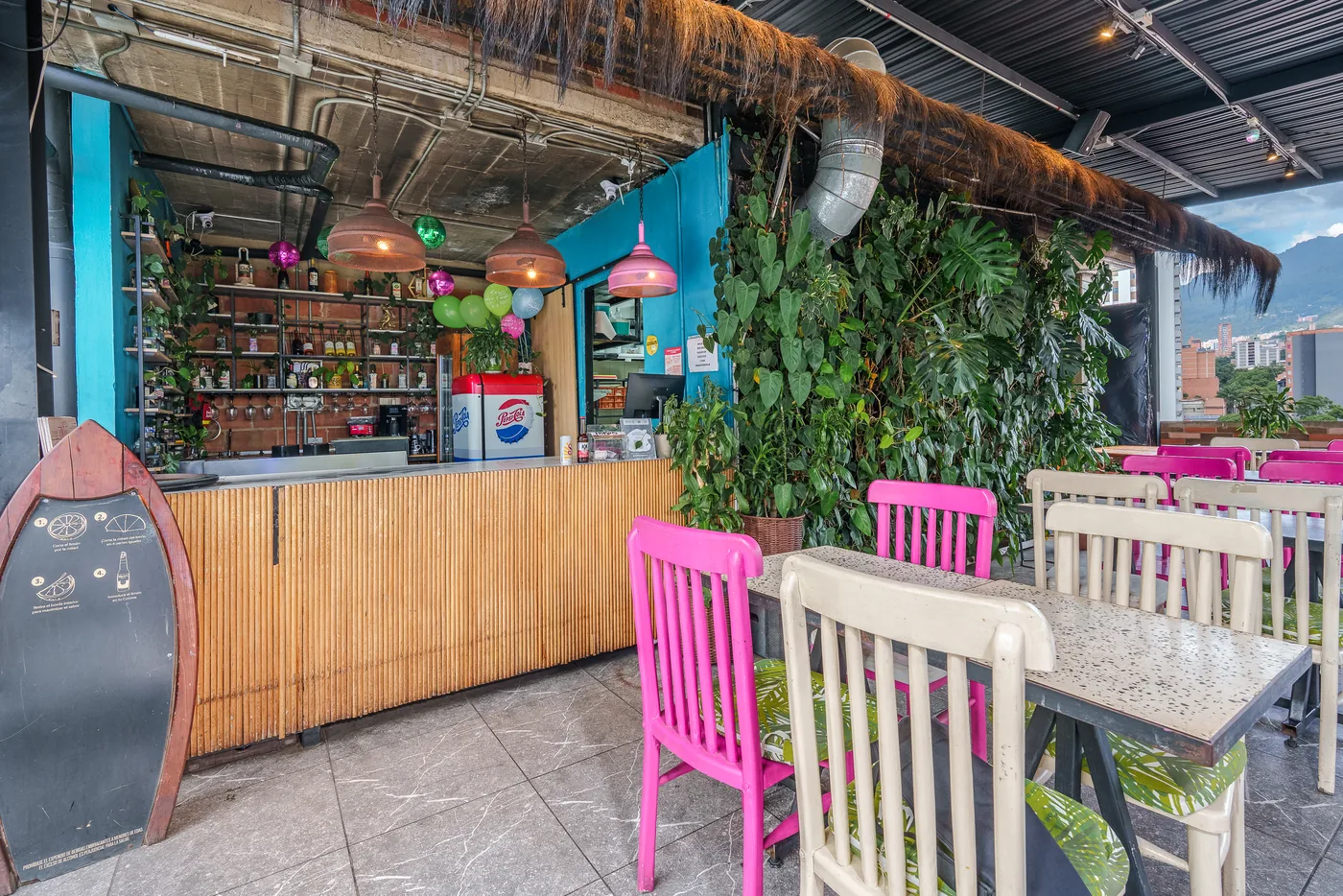Zona de mesas del bar-restaurante de la azotea, con plantas y vista a la ciudad